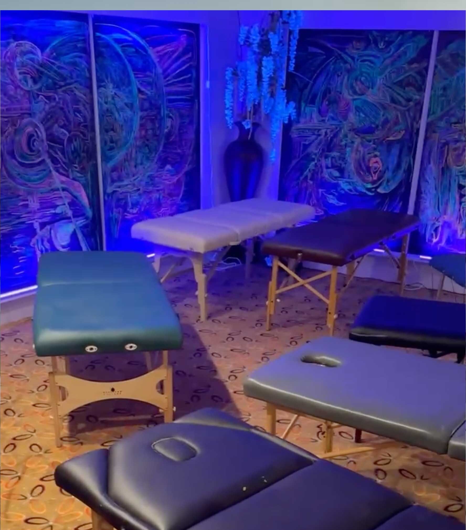 room with psychedelic wall art, blacklight and massage tables